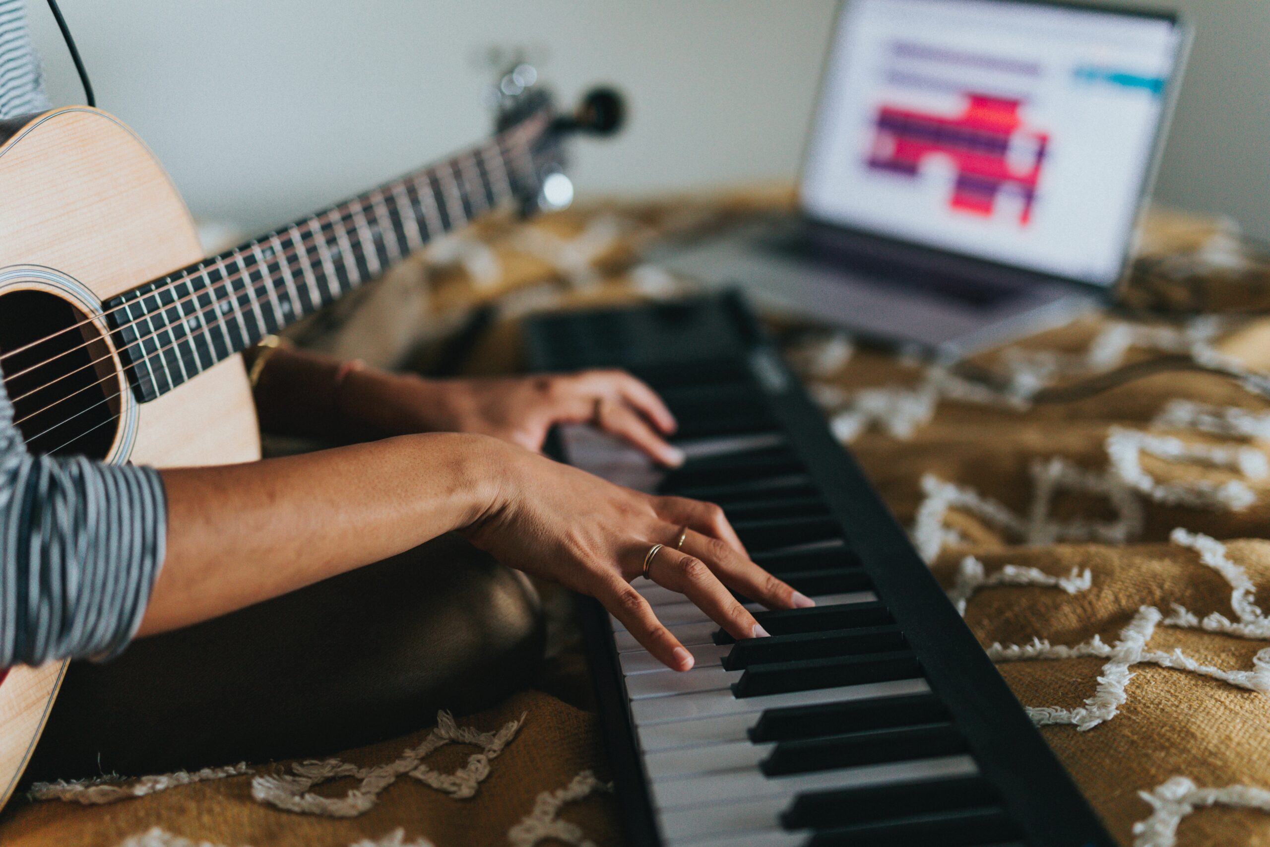 Person playing keyboard while holding guitar