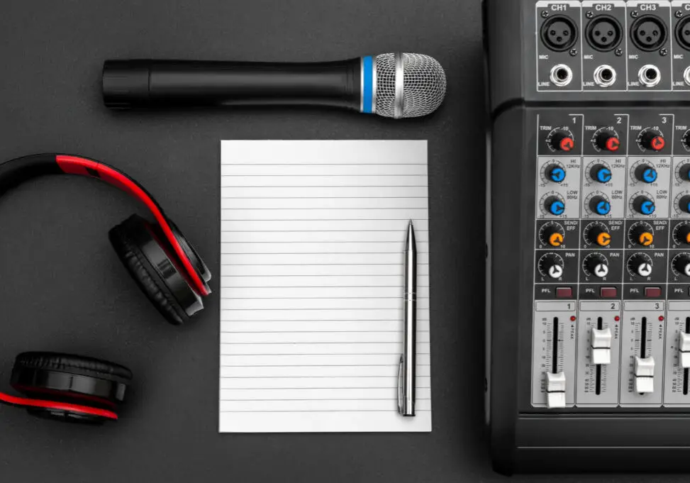 Notepad with audio sound mixer, microphone and headphones on black. Top view.